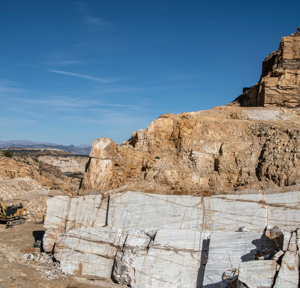 A scenic quarry featuring massive rock formations and an excavator in operation.